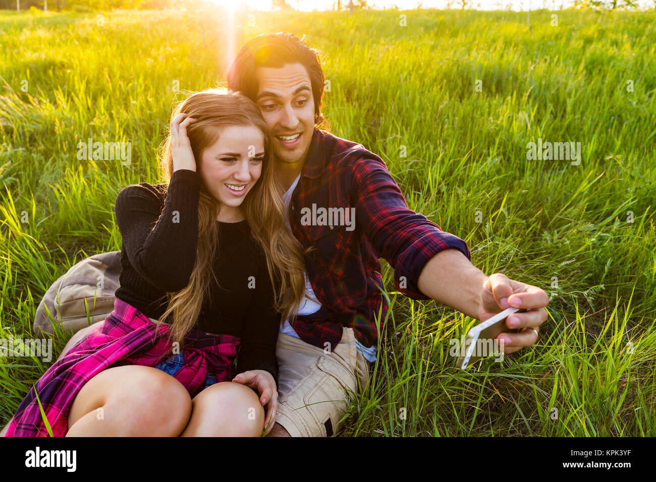 Junges Paar in einem Park für einen selbst posiert - Porträt mit ihrem Handy, Edmonton, Alberta, Kanada Stockfoto