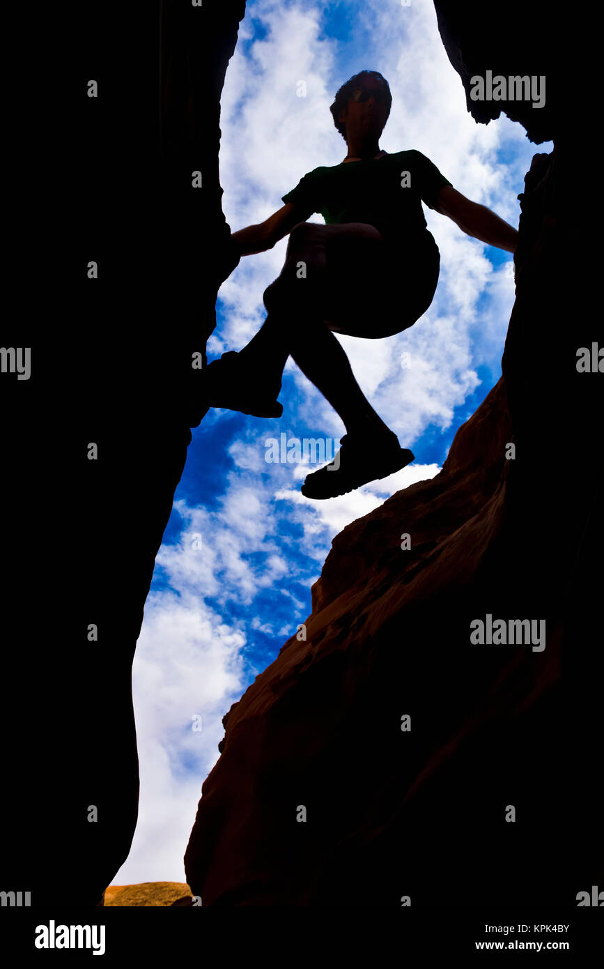Nach oben, um die Silhouette eines Bergsteiger in einen Slot Canyon in der Wüste; Hanksville, Utah, Vereinigte Staaten von Amerika Stockfoto