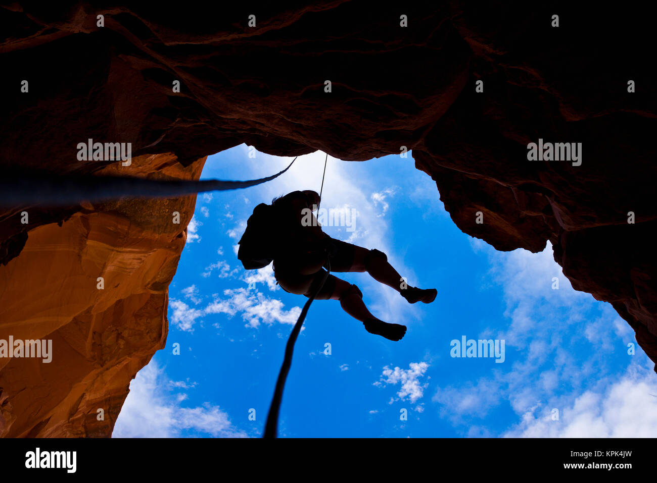 Nach oben, um die Silhouette eines Abenteurers abseilen, eine Schlucht in der Wüste; Hanksville, Utah, Vereinigte Staaten von Amerika Stockfoto