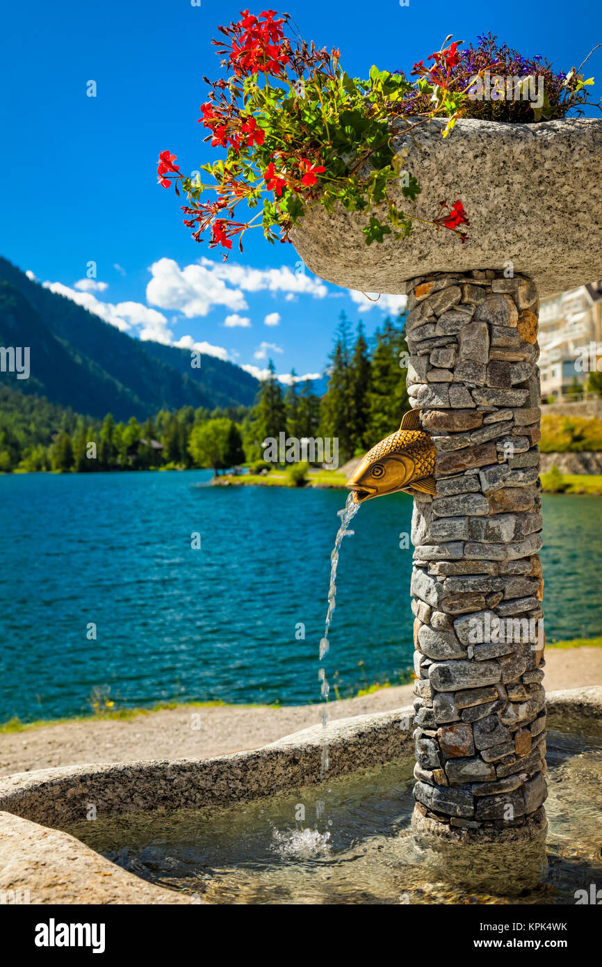 Nahaufnahme einer Steinbrunnen mit blumentöpfe von Champex See und Gebirge im Hintergrund; Champex, Wallis, Schweiz Stockfoto Nahaufnahme einer Steinbrunnen mit blumentöpfe von Champex See und Gebirge im Hintergrund; Champex, Wallis, Schweiz Stockfoto