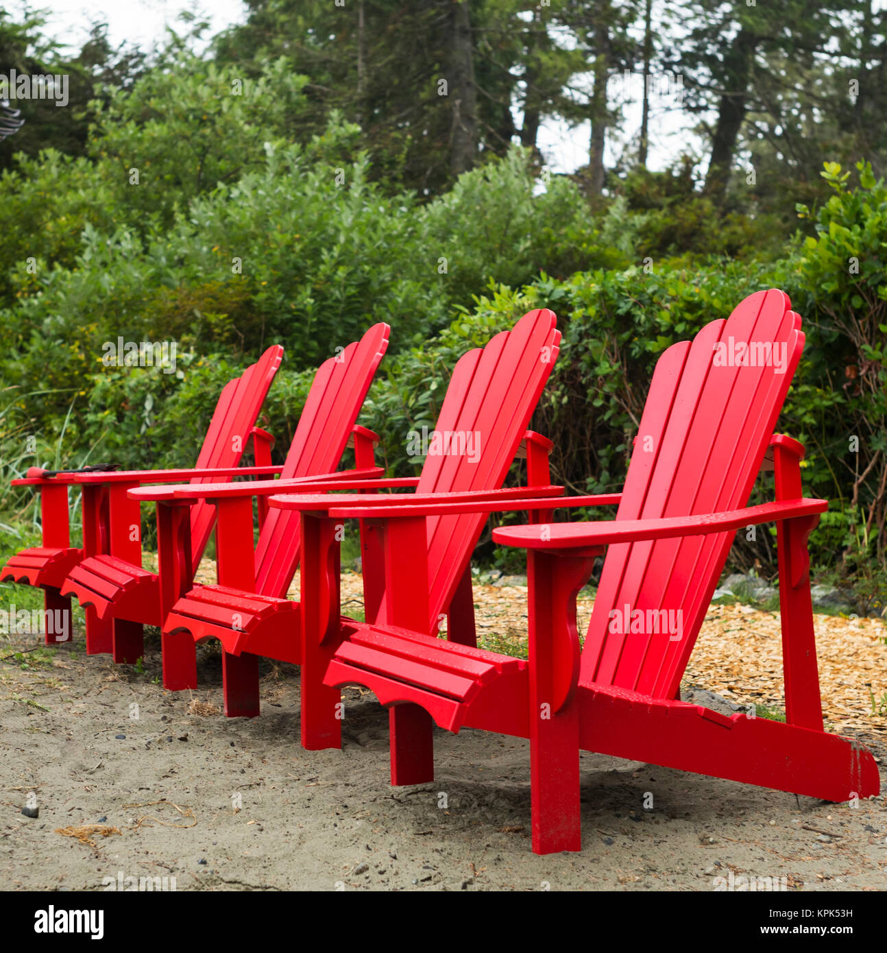 Vier rote Adirondack Stühle in einer Reihe auf Chesterman Beach, Vancouver Island, Pacific Rim; Tofino, Britisch-Kolumbien, Kanada Stockfoto