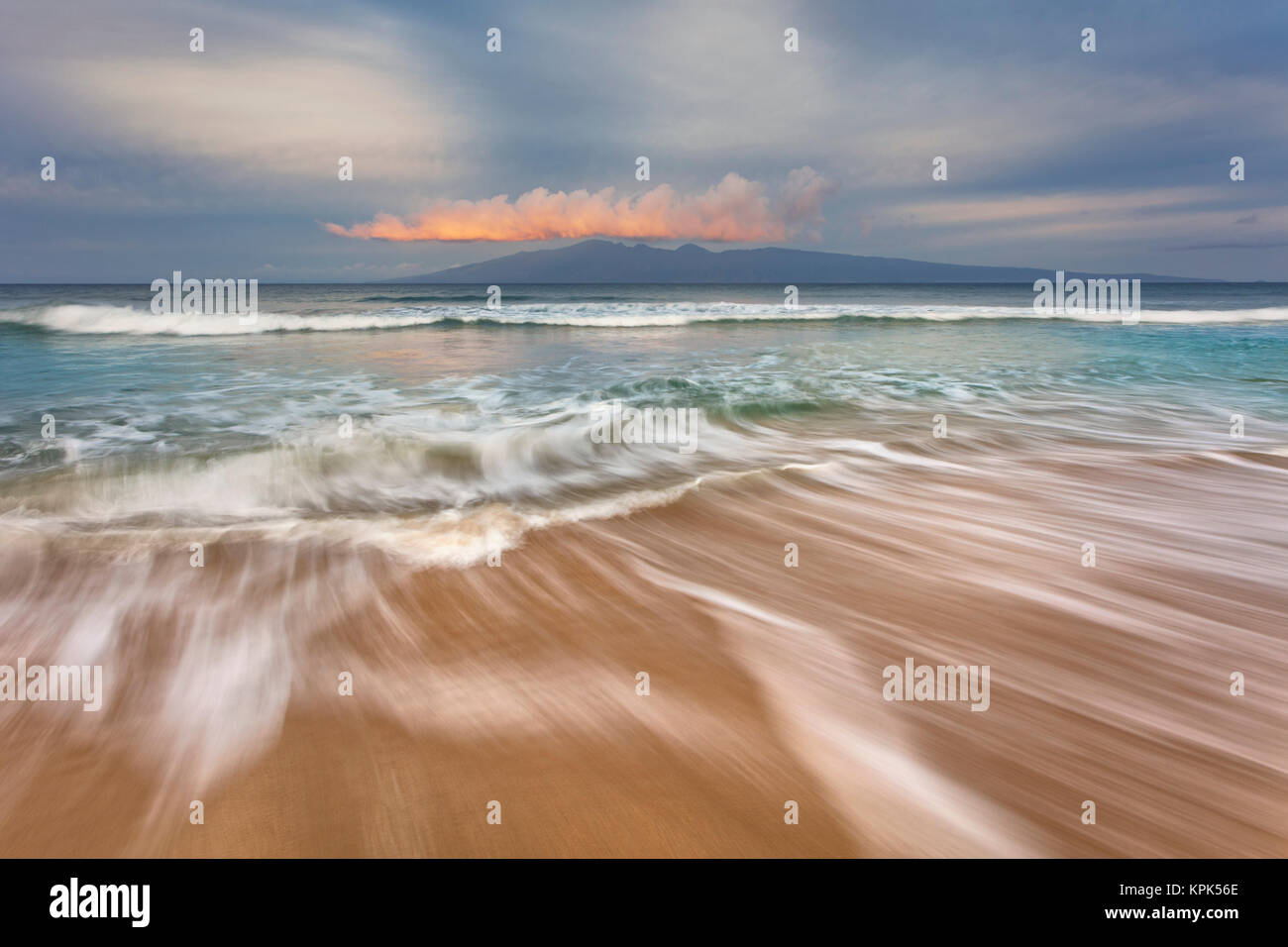 Weiches Wasser erstreckt sich über den Sand bei Sonnenaufgang mit Blick auf Molokai; Maui, Hawaii, Vereinigte Staaten von Amerika Stockfoto