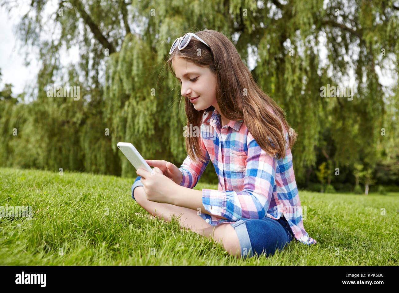 Jugendliche Mädchen in einem Park mit einem Tablet-PC sitzen; Toronto, Ontario, Kanada Stockfoto