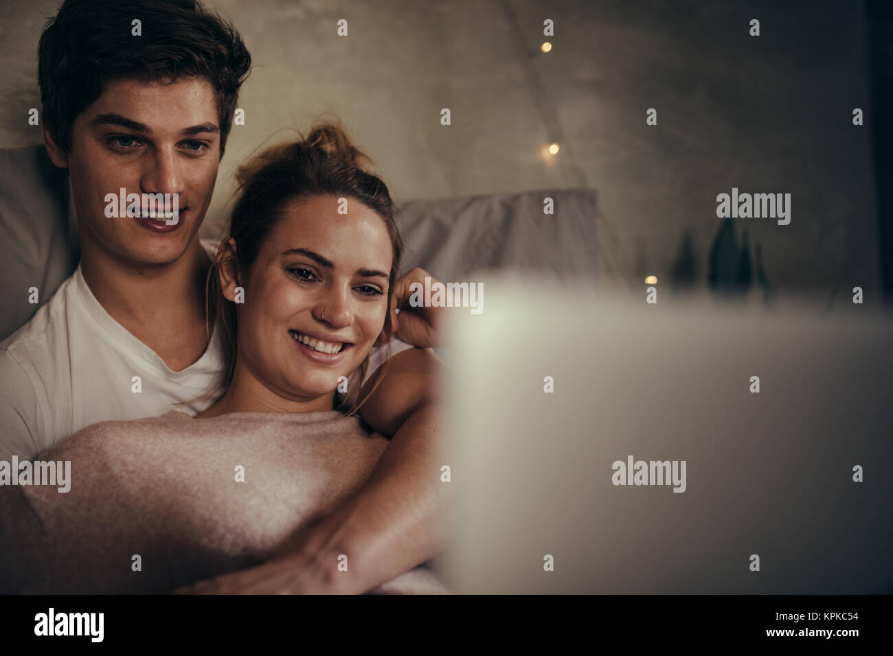 Hygge paar Videos auf Laptop im Schlafzimmer. Lieben jungen Mann und Frau mit Laptop auf dem Bett. Stockfoto