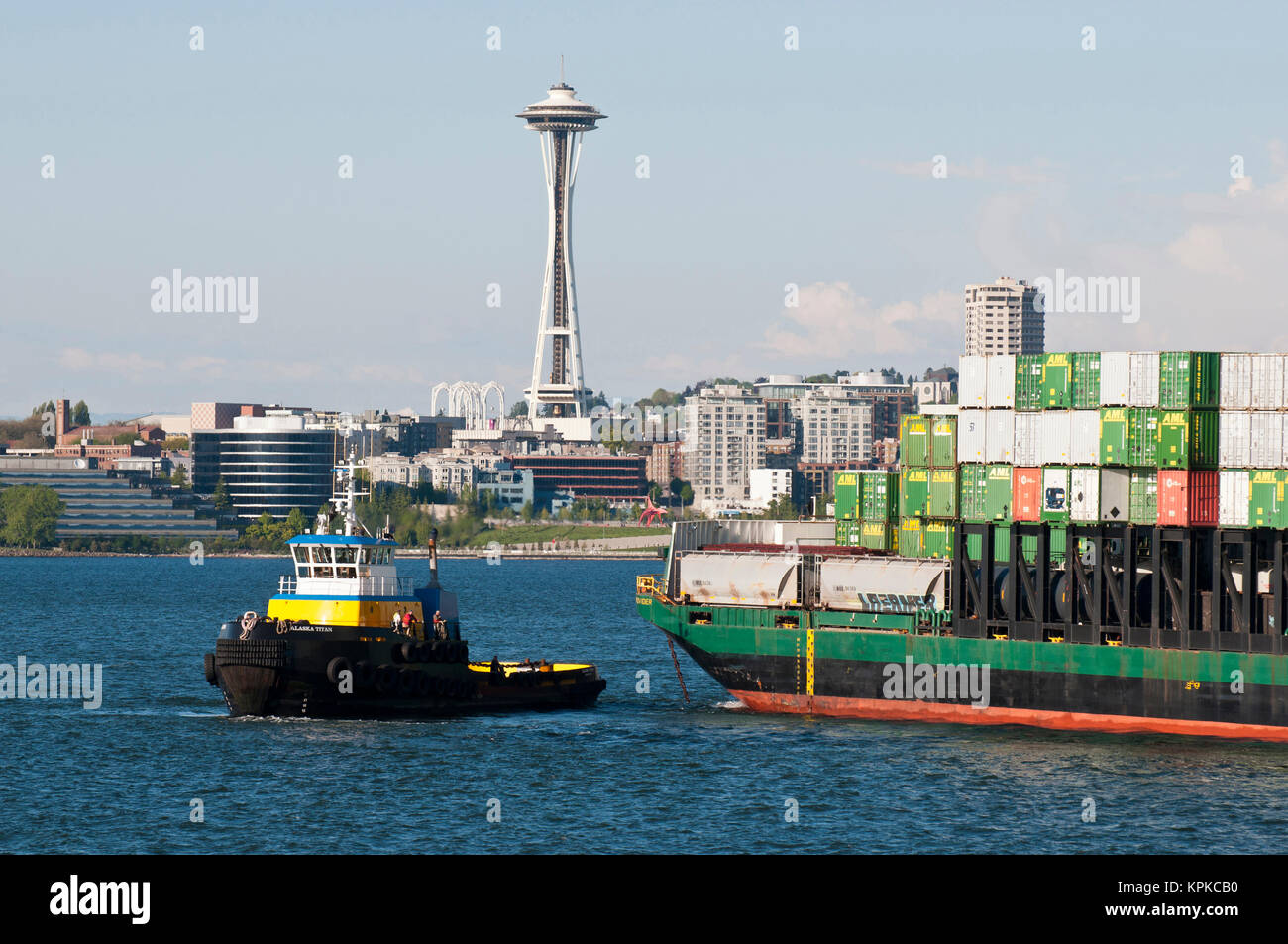 Uns, WA, Seattle, Puget Sound, King County. Tugboat stellt Container schiff in der Elliott Bay mit Seattle Waterfront und Space Needle als Hintergrund zu unterstützen. Stockfoto