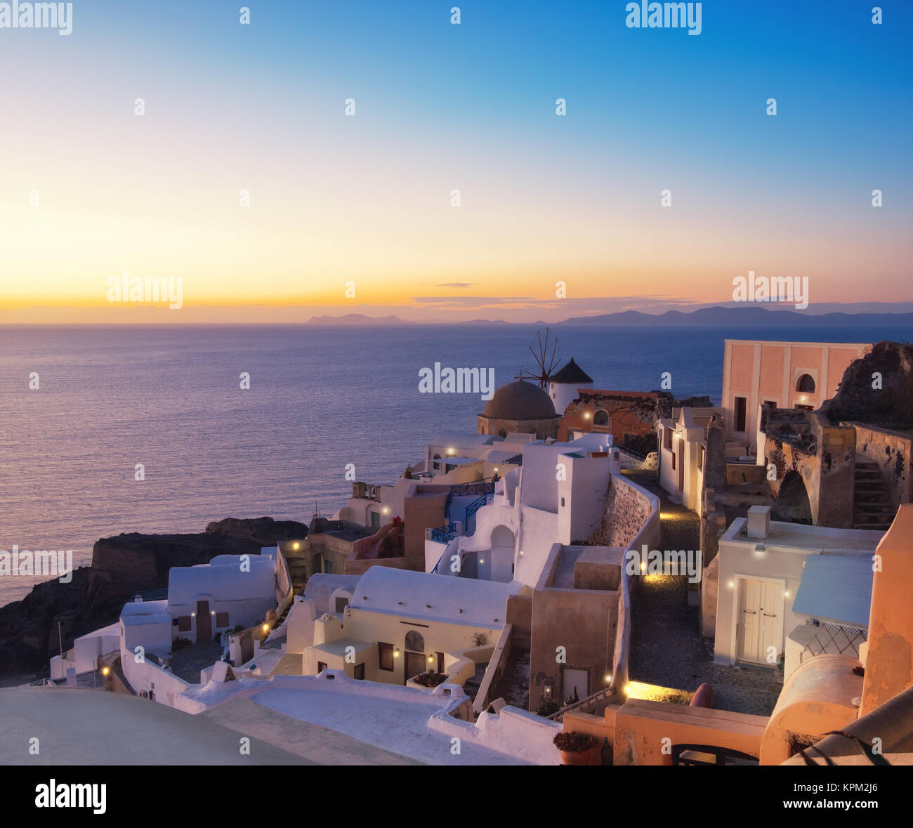 Santorini in Griechenland - traditionelle Windmühle und Apartments in Oia nach Sonnenuntergang, panorama bild. Stockfoto