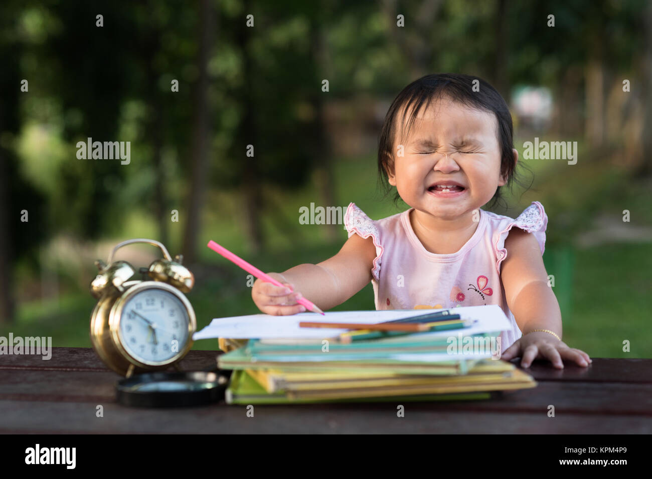 Asiatische Baby Kleinkind Zeichnung im Park, während sie lustiges Gesicht Stockfoto