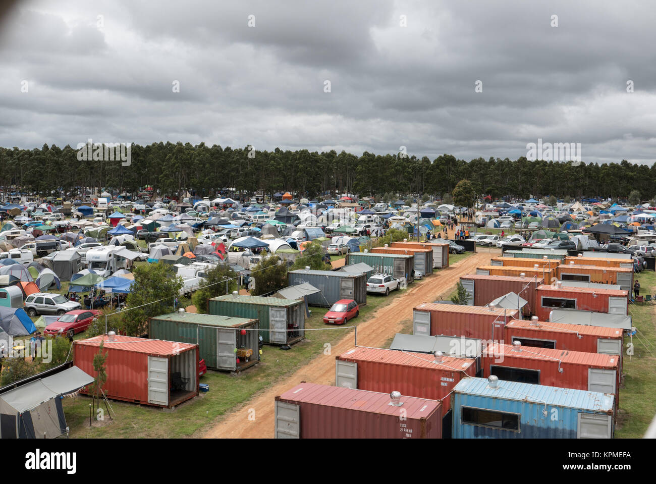 Luftaufnahme von sehr großen Music Festival Campingplatz mit Shipping Container unterkunft Zelte, Anhänger, Autos und Wald im Abstand. Stockfoto
