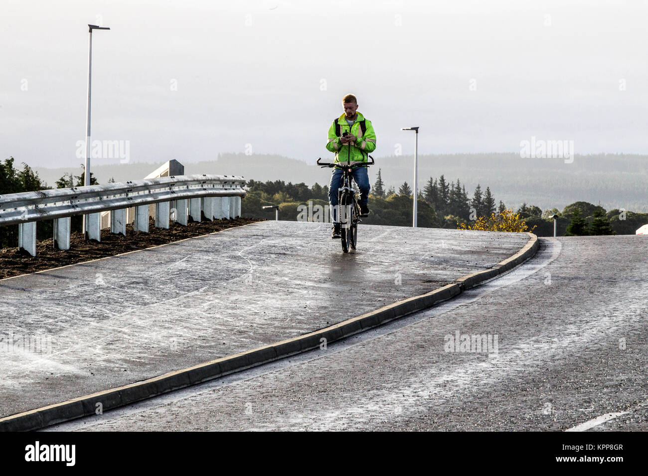 Radfahrer mit Handy während Radfahren auf der Fahrbahn/Gehweg Stockfoto
