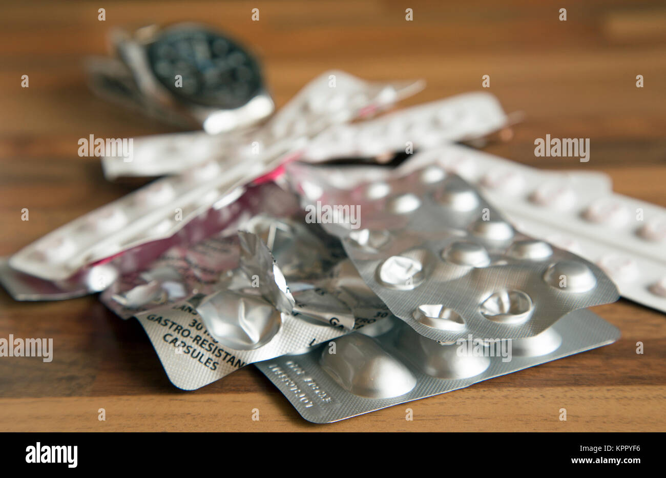 Ein Haufen Teil verwendet verschreibungspflichtige Medikamente auf einer Tischplatte mit eine Uhr im Hintergrund Schuß im Querformat. Stockfoto