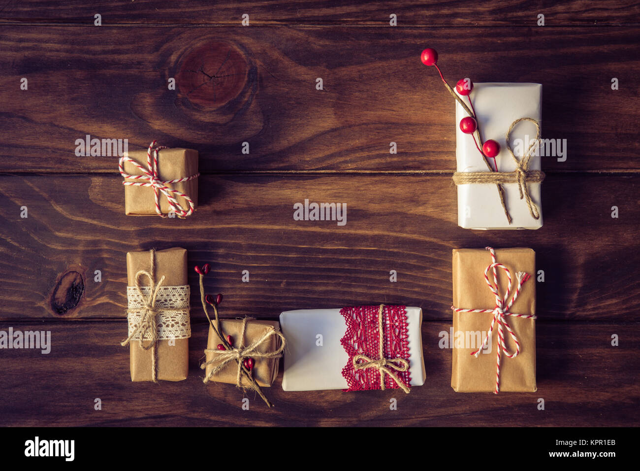 Weihnachten Geschenke durch festliche Dekoration über braune Holztisch eingerichtet. Dunklen rustikalen Stil. Ansicht von oben. Getönt mit alten Stil sepia Farben. Weihnachten und Cele Stockfoto