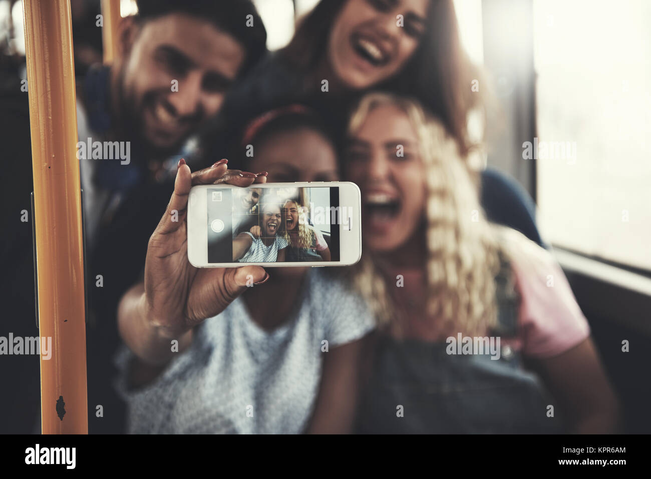 Lächelnd Gruppe von verschiedenen jungen Freunde unter selfies zusammen mit einem Smartphone beim Reiten auf einem Bus Stockfoto