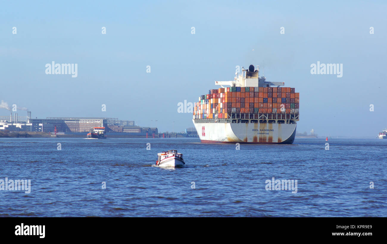 HAMBURG, DEUTSCHLAND - 8. März, 2014: großes Containerschiff auf dem Wasser mit Hafen Docks im Hintergrund unter blauem Himmel Stockfoto