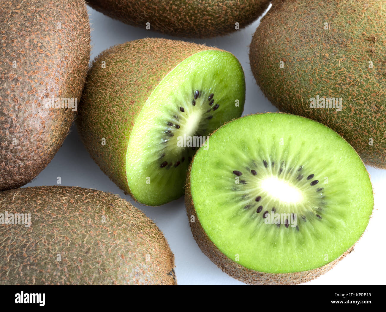 Grüne Kiwi in der Hälfte neben ganzen auf weißem Hintergrund Stockfoto