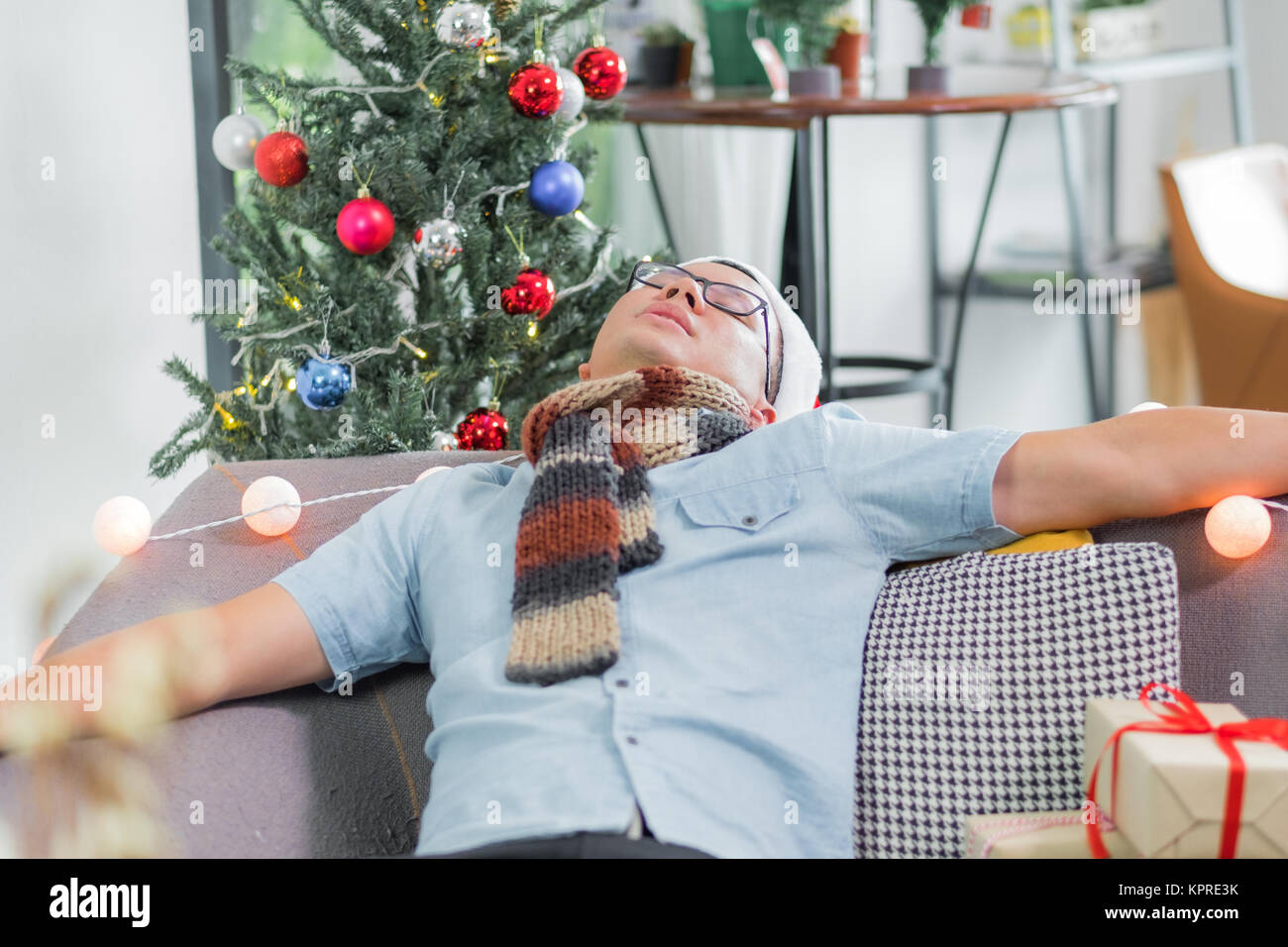 Asien mann Kater und ging schlafen auf dem Sofa nach schweren Weihnachten und Neues Jahr Partei beenden und auf der Couch bis zum Morgen feiern Feiertag sogar Stockfoto
