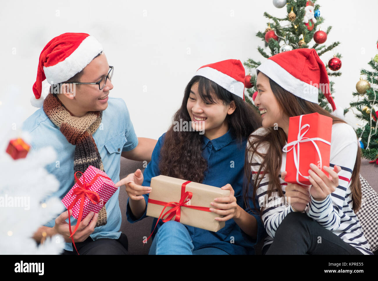 Gruppe von Asien Freunde sitzen auf einem Sofa feiern Weihnachten und Silvester Party mit Geschenk Austausch auf schmücken Baum, Geschenke urlaub Konzept. Glück Stockfoto