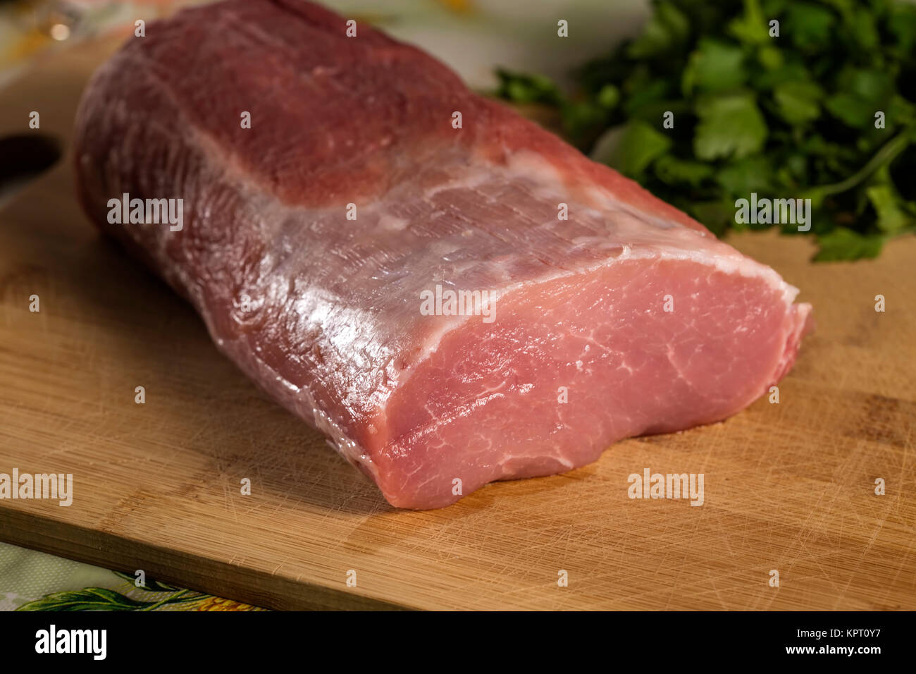 Rohes Schweinefleisch auf Holz Schneidbrett chop mit Petersilie im Hintergrund Stockfoto