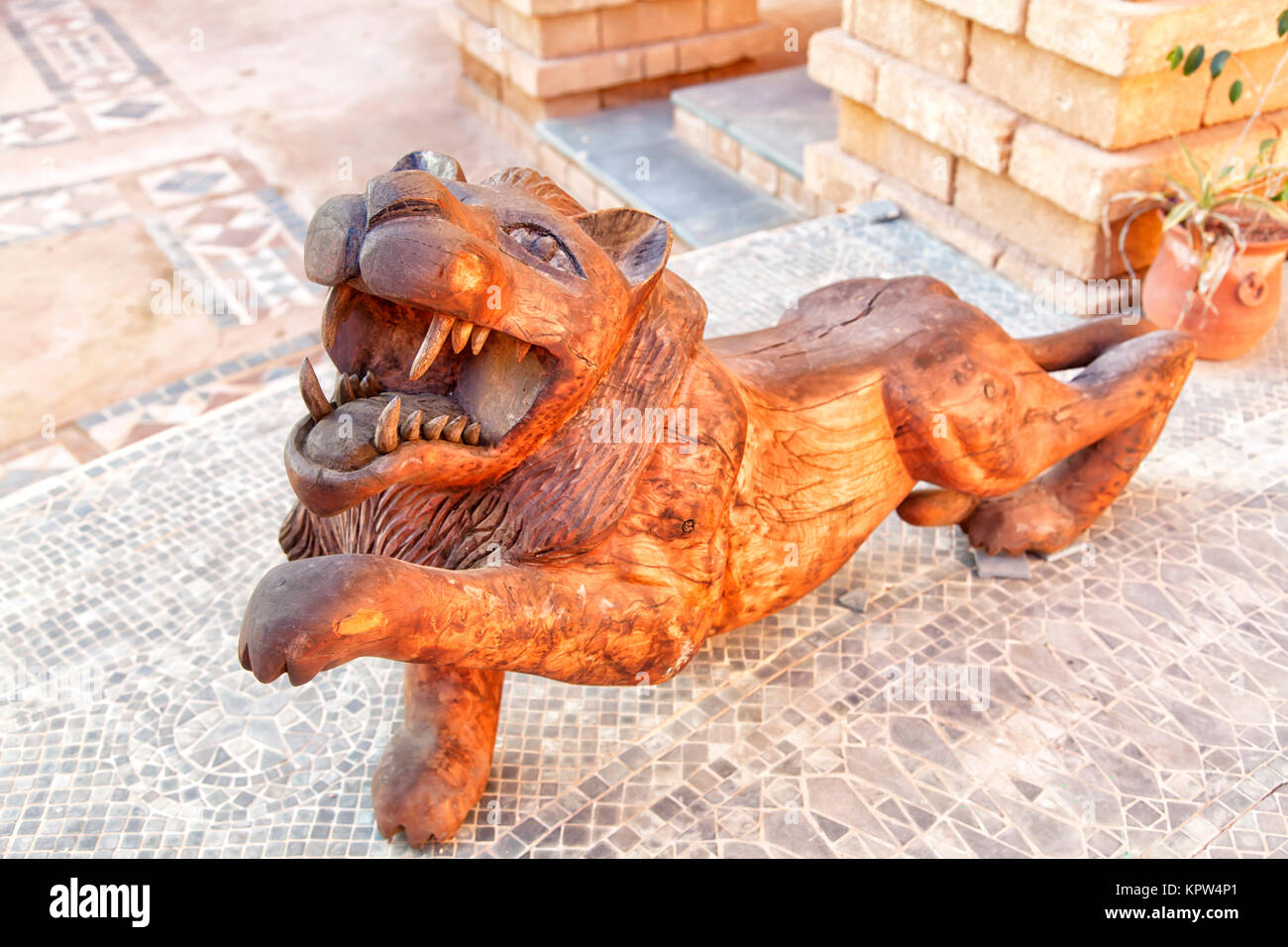 Ein Löwe als Holzskulptur e in einem Innenhof n der Medina der afrikanischen Hafenstadt Agadir in Marokko Stockfoto