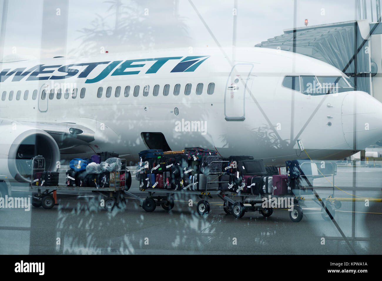 Künstlerische Foto von einem Gepäckträger Zug voller Gepäck über auf einem WestJet Flugzeug Der internationale Flughafen in Victoria, BC, Kanada 201 geladen werden. Stockfoto