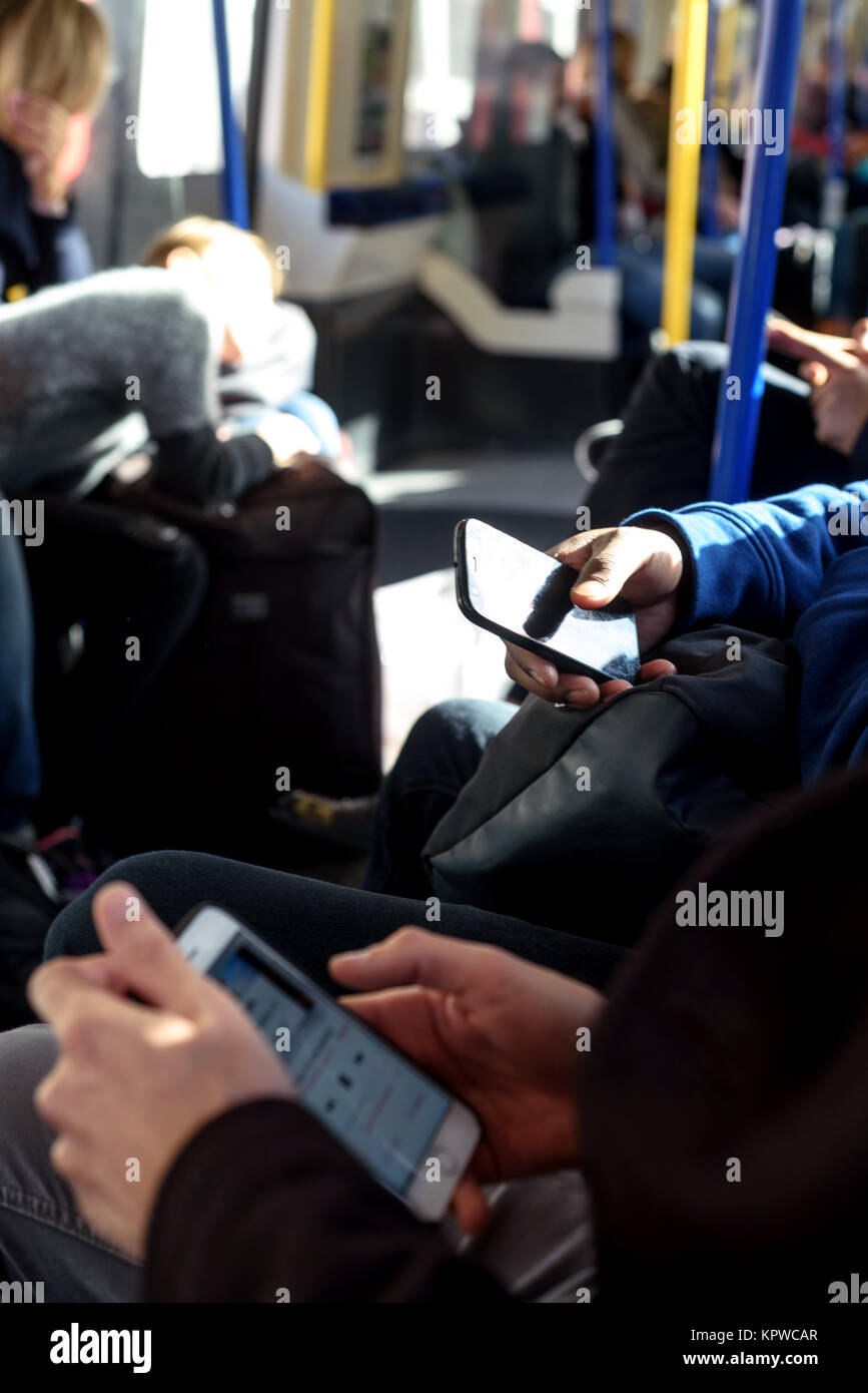 Menschen, die ihre Smartphones während der Fahrt die Londoner U-Bahn Stockfoto