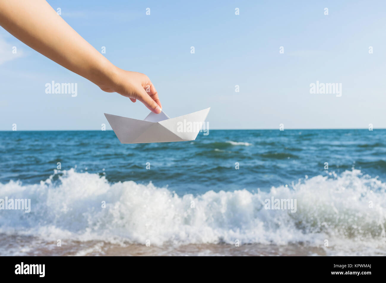 Weibliche Hand, die eine neue Boot auf dem Meer Hintergrund Stockfoto