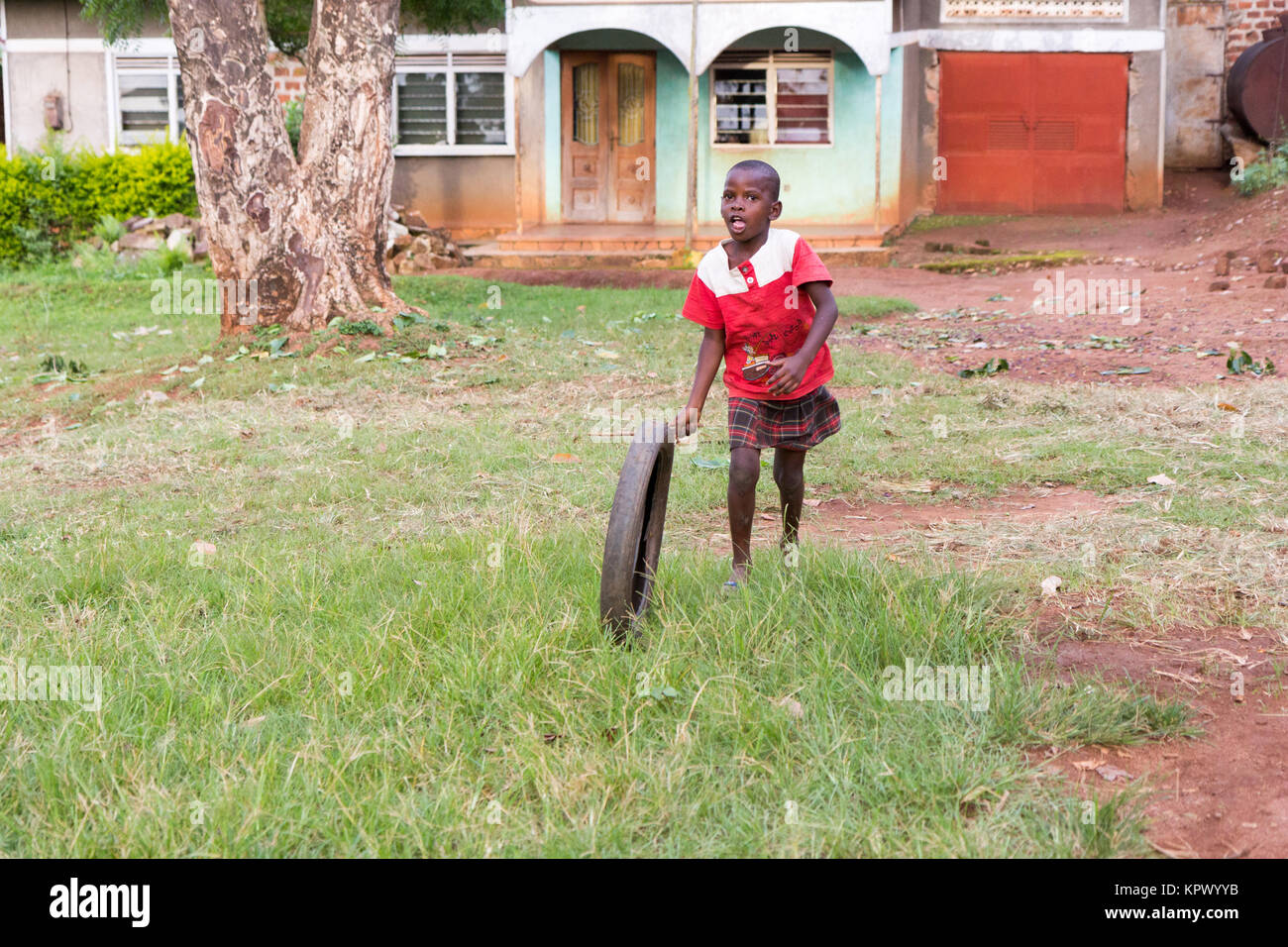 Eine ugandische Kind Dreht ein Rad Reifen. Stockfoto