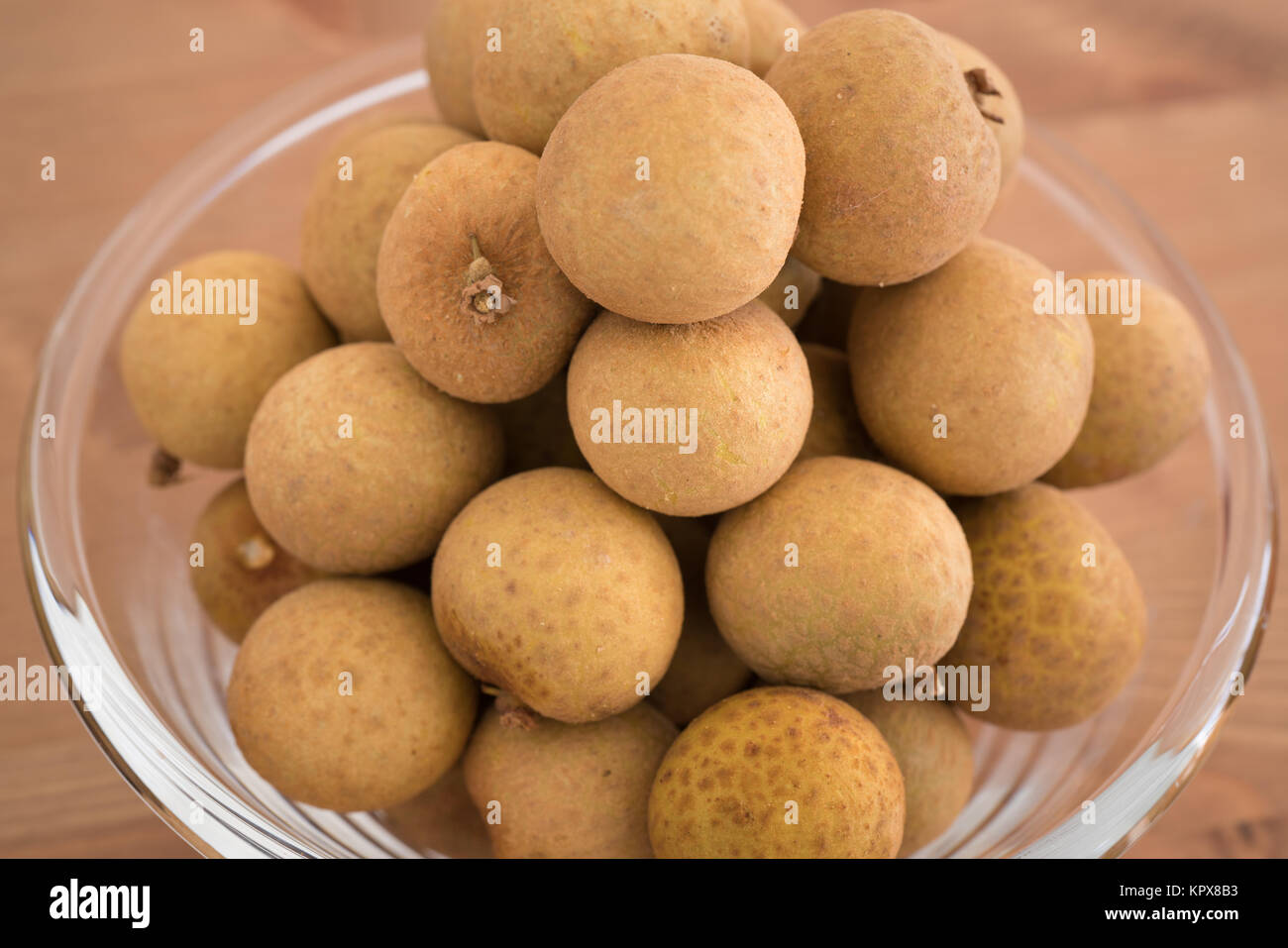 Schüssel gefüllt mit einem Haufen Dimocarpus Longan Früchte auf hölzernen Hintergrund isoliert Stockfoto