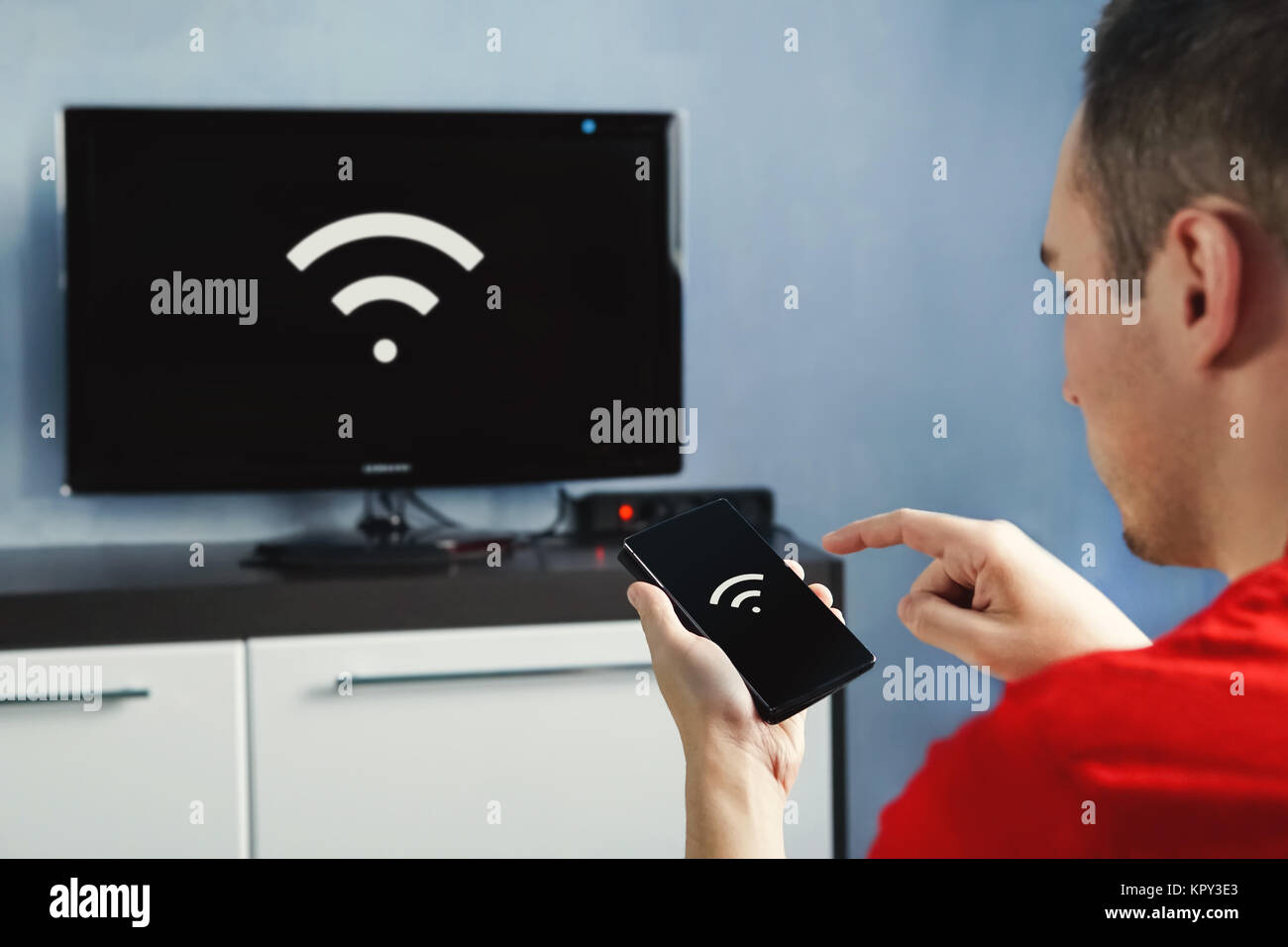 Die Konnektivität zwischen Smart TV und Smart Phone durch wifi-verbindung. Steuern Sie Ihren Fernseher mit Ihrem Smartphone. Das WLAN-Symbol auf dem Telefondisplay und das Stockfoto
