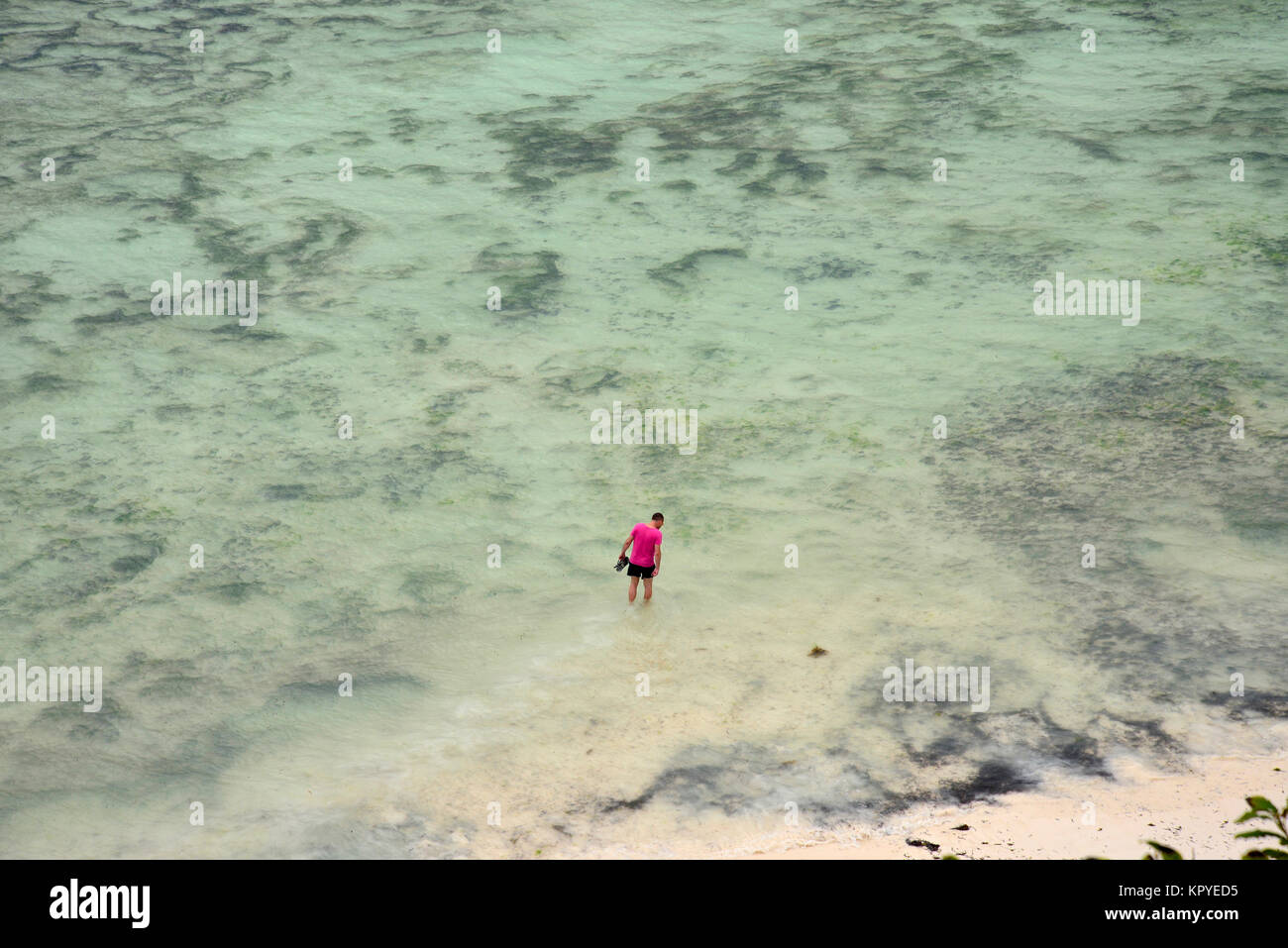 Sansibar ist eine Indische Ozean Paradies, das die meisten Menschen es sich leisten können, für faule Ferien auf warmen Strände zu besuchen. Man Waten in Meer, Luftbild. Stockfoto