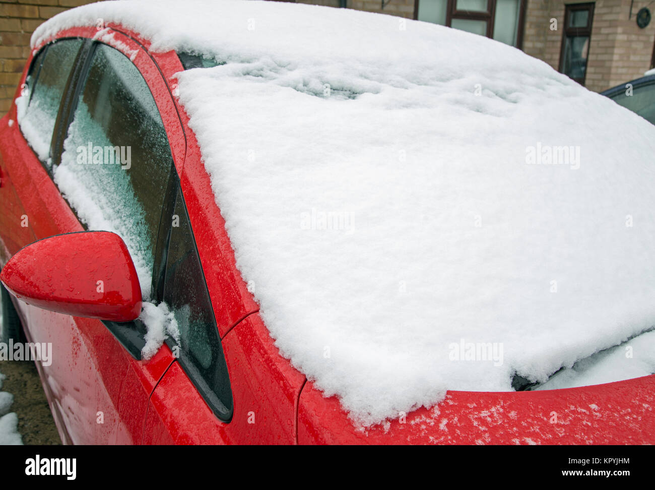 Landschaft geschossen von Schnee, der auf die Windschutzscheibe von einem roten Auto gefallen ist. Stockfoto