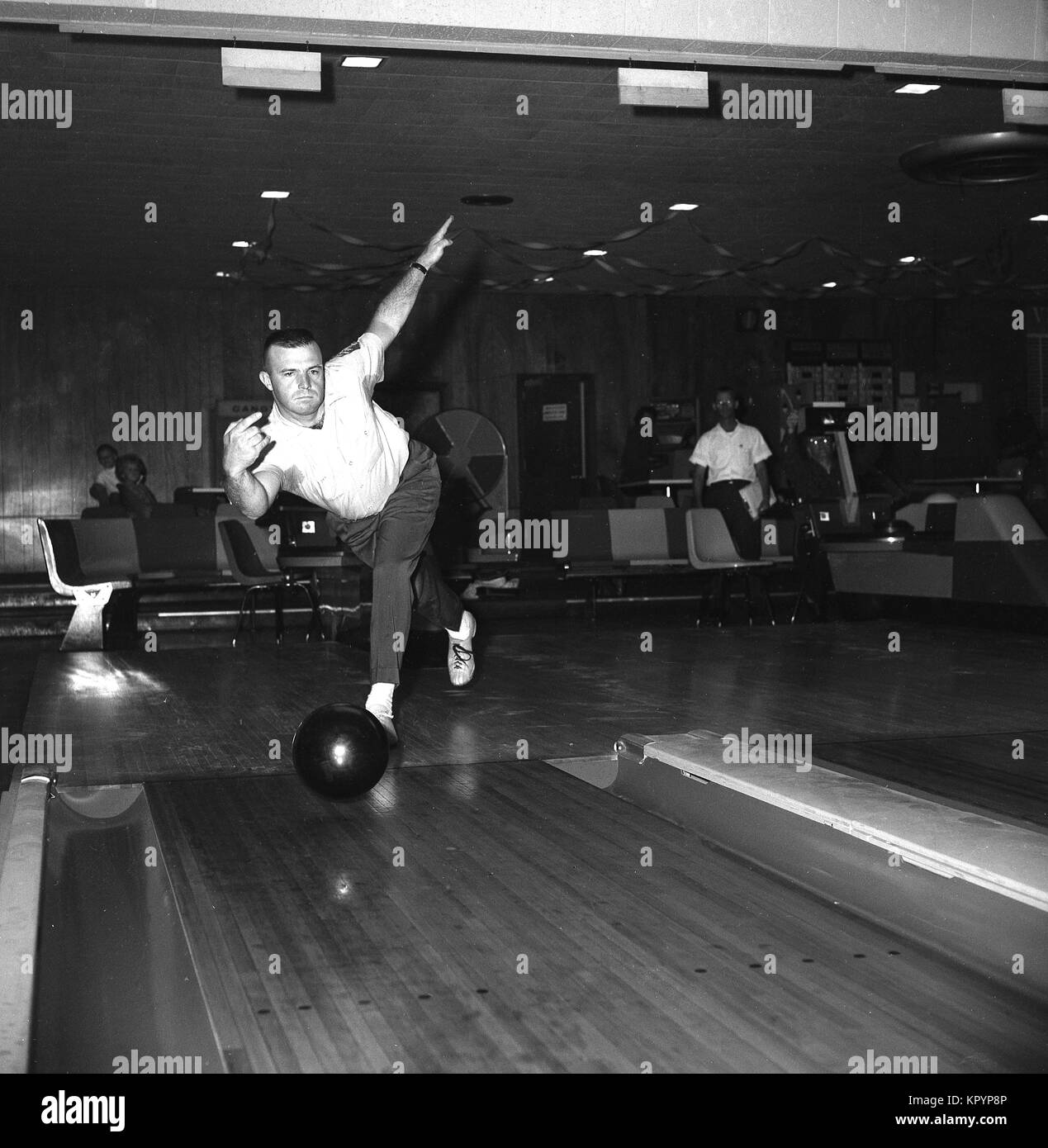 1960, historische, Ten-pin Bowling, einem Mann einen bolwling Kugel ungefähr halten Sie sie in eine Spur am 10 werfen - pin bolwling Gasse, USA. Stockfoto