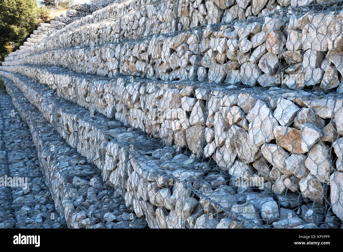 Eine Reihe von trat zurück Gabionen, Stein gefüllt Käfige, Linie a Mountain Road Schutz der Damm von Erosion und zum Schutz der Straße. Stockfoto