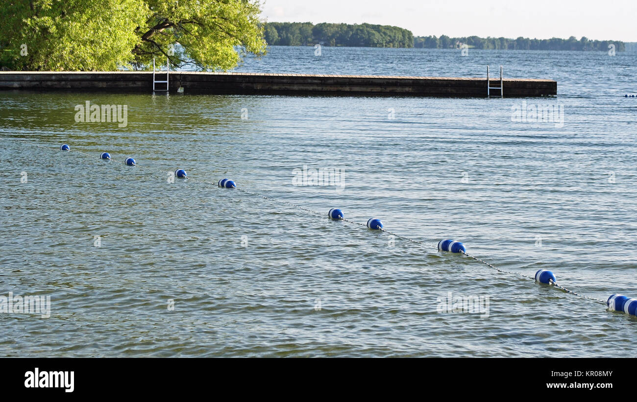 Bojen Aneinanderreihen von Seil entlang der wunderschönen blauen See sicher Schwimmen für Schwimmer zu erstellen. Mit Leiter im Hintergrund Dock. Keine Menschen. Stockfoto