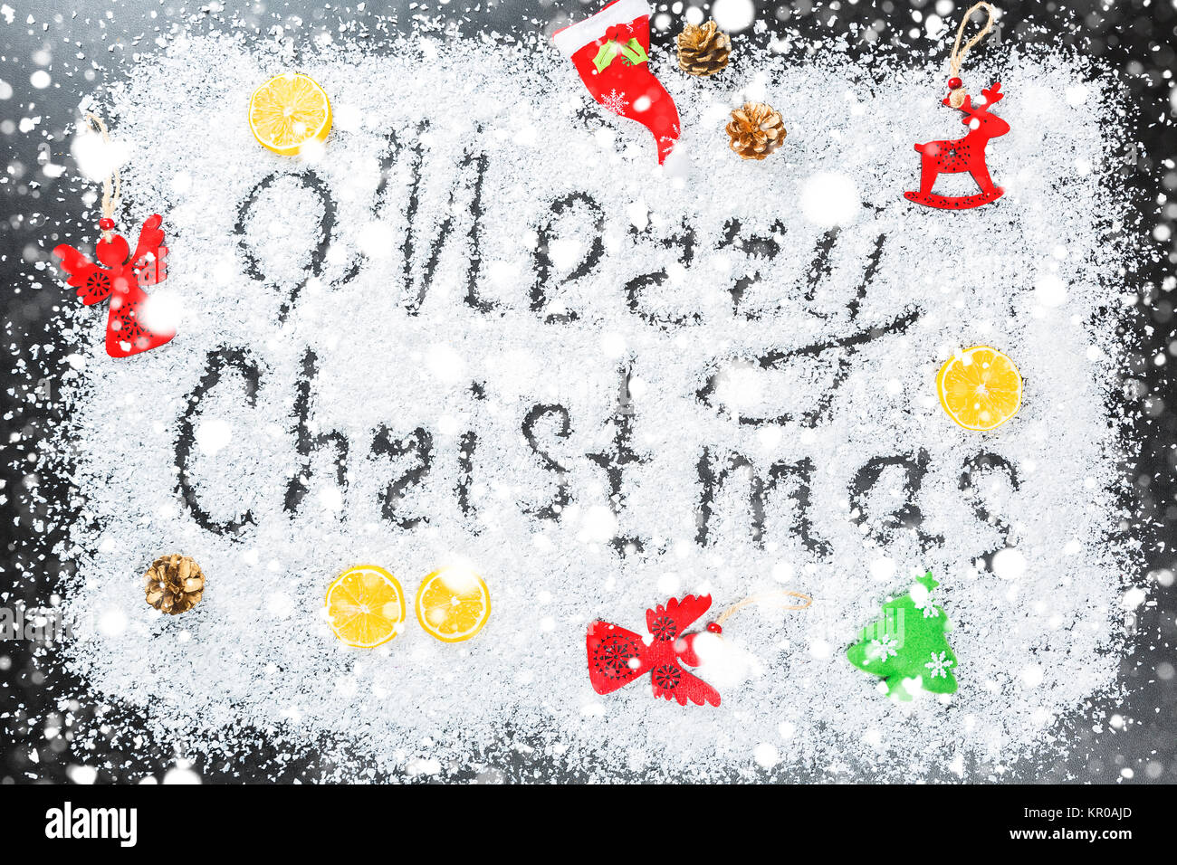 Weihnachten Hintergrund mit der Aufschrift Frohe Weihnachten auf weißem Schnee mit Holzspielzeug, Zitrone, Schneeflocken und Neues Jahr eingerichtet. Winterurlaub Stockfoto