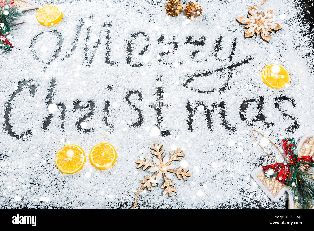 Weihnachten Hintergrund mit der Aufschrift Frohe Weihnachten auf weißem Schnee mit Holzspielzeug, Zitrone, Schneeflocken und Neues Jahr eingerichtet. Winterurlaub Stockfoto