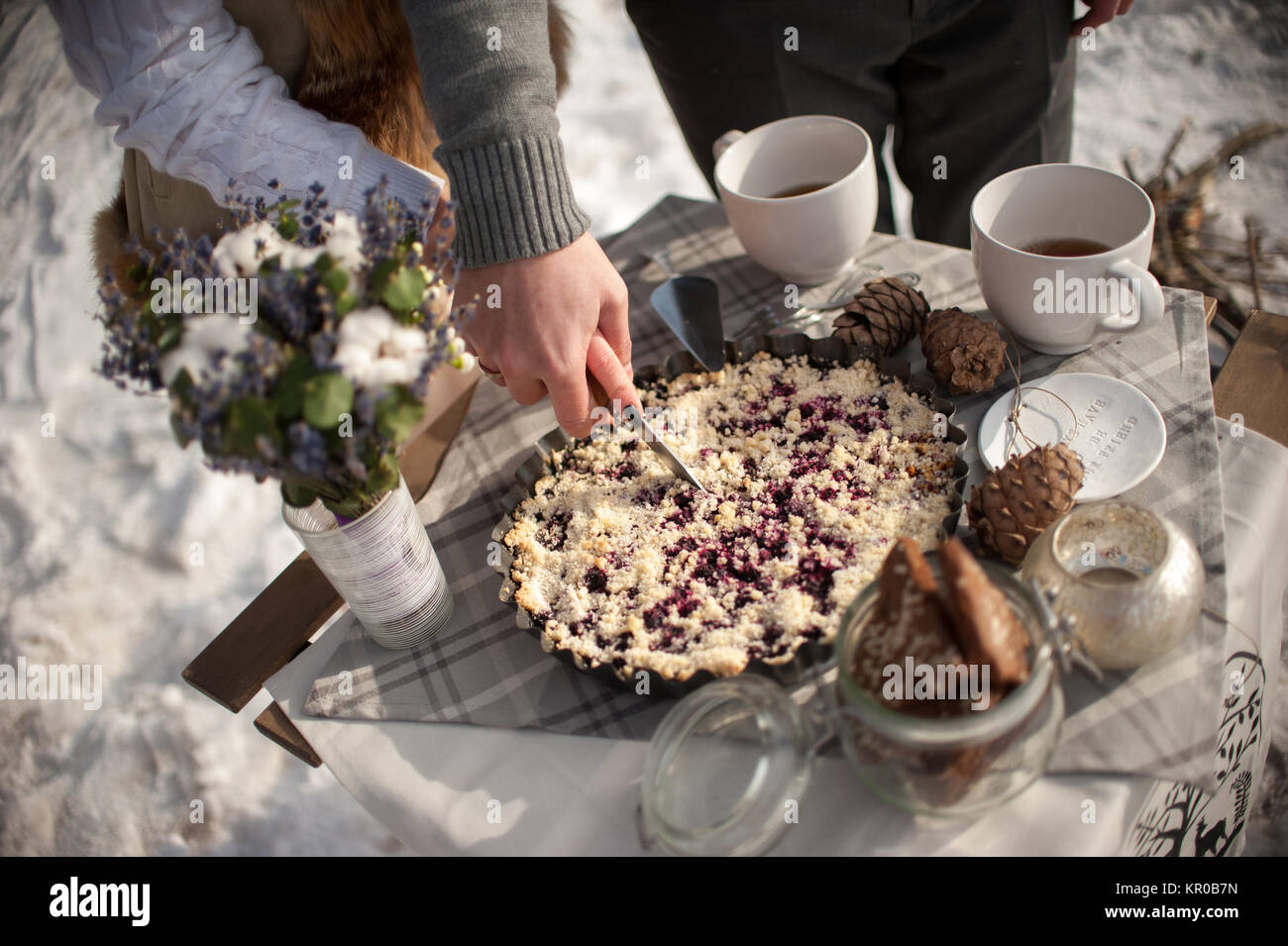 Die Braut und Bräutigam schneiden die Hochzeitstorte in Zinn Metallplatte im Freien im Winter an der Küste von den zugefrorenen Fluss Stockfoto