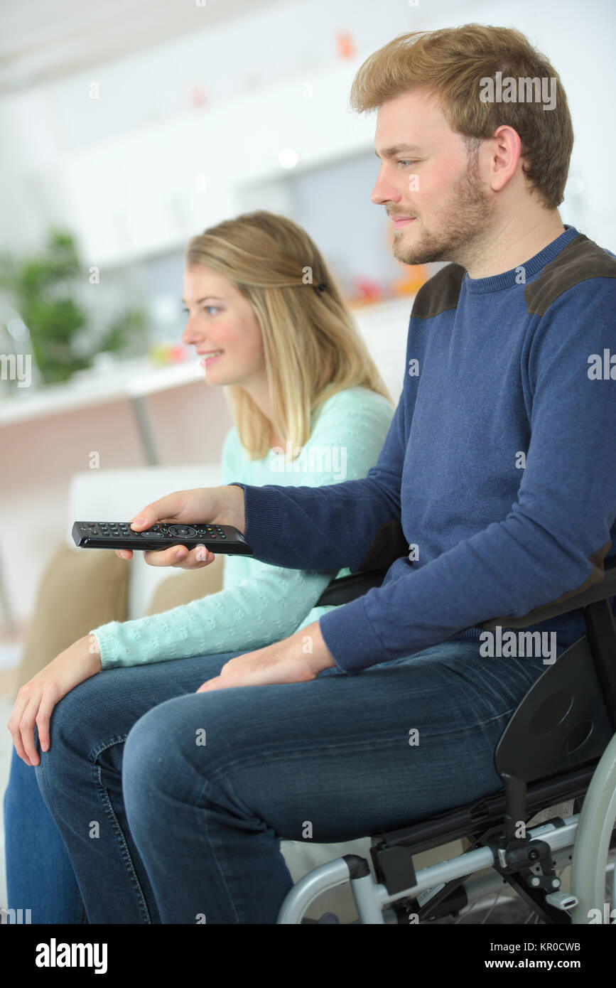 Behinderte Mensch vor dem Fernseher mit seiner Freundin Stockfoto