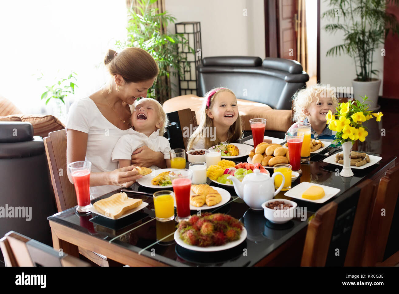 Gesunde Familie Frühstück zu Hause. Mutter und Kinder essen, tropische Obst, Toast, Brot, Käse