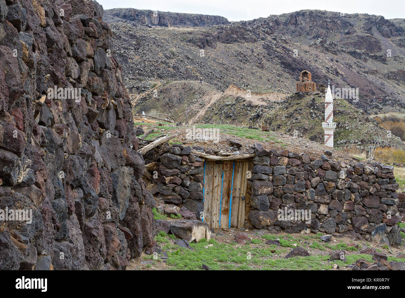 Häuser aus Stein in der Kilittas Dorf in Kars, Türkei, an der Türkischen, armenischen Grenze. Die weißen Minarett ist in der Türkei und in der Kirche in Armenien. Stockfoto