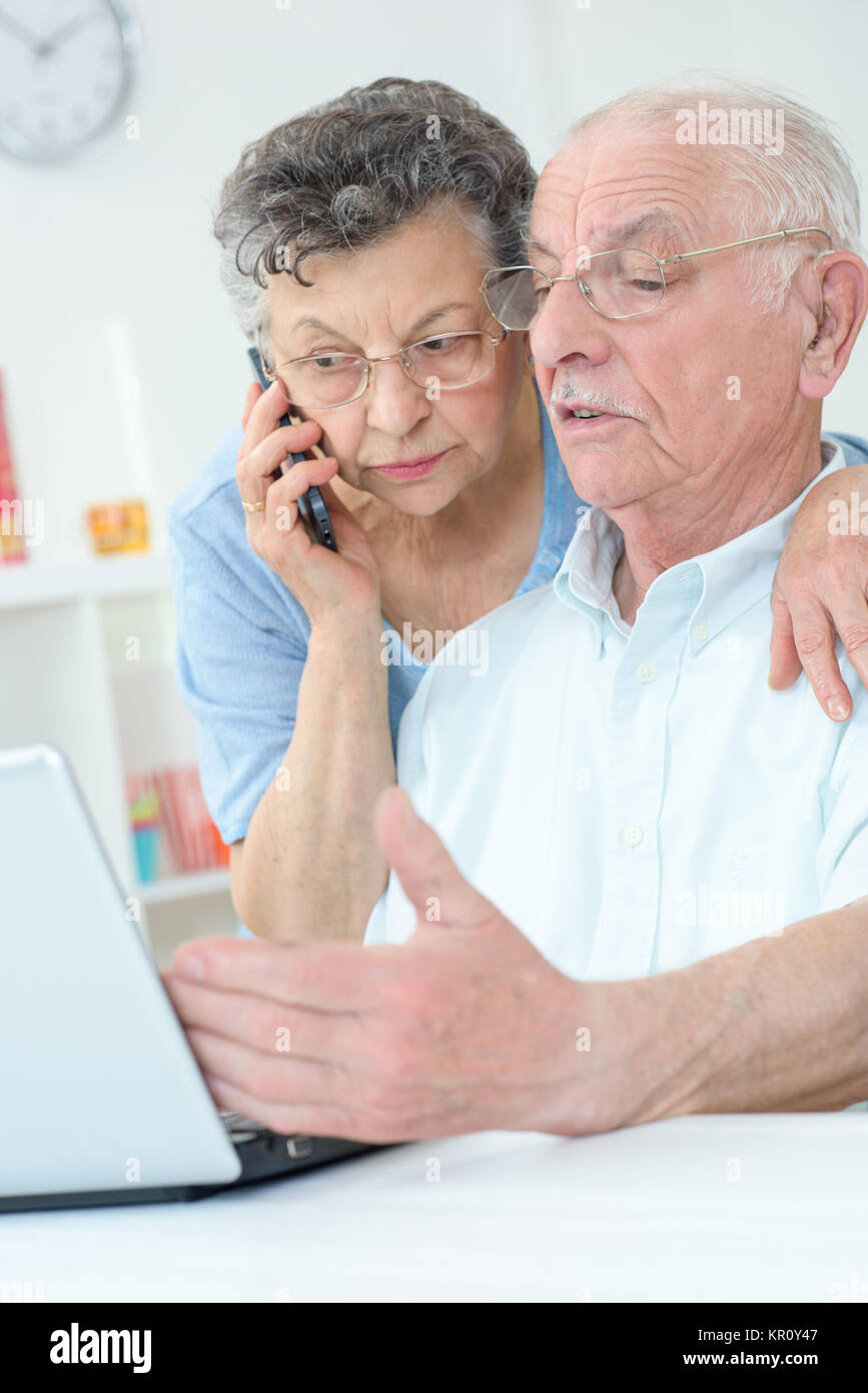 Ältere Paare mit Laptop, die Frau am Telefon Stockfoto
