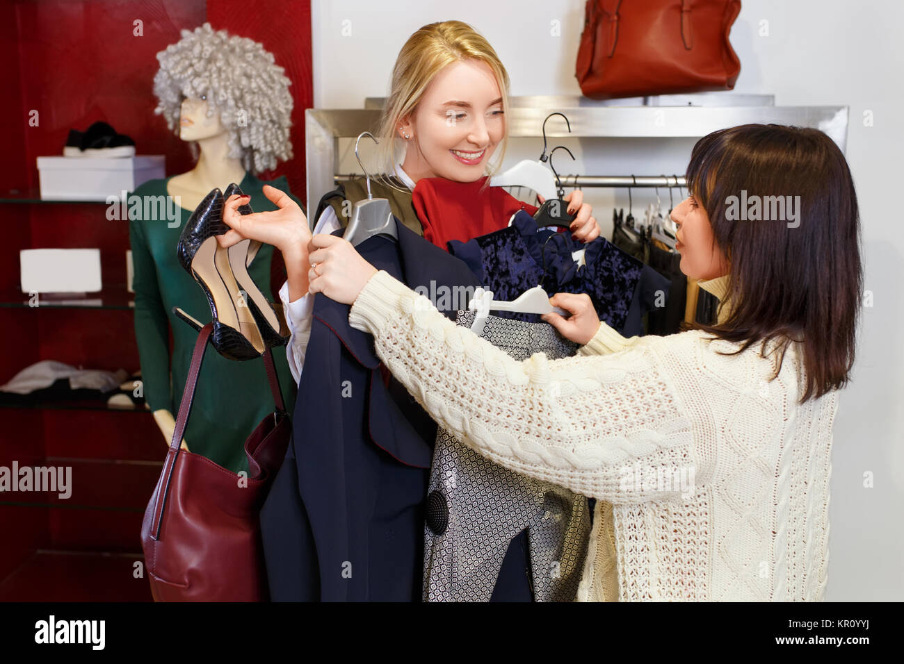 Sales Consultant helfen wählt Kleidung für den Kunden in der Filiale. Shopping mit Stylistin. Female Shop Assistant consulting junge Frau in der Fas Stockfoto