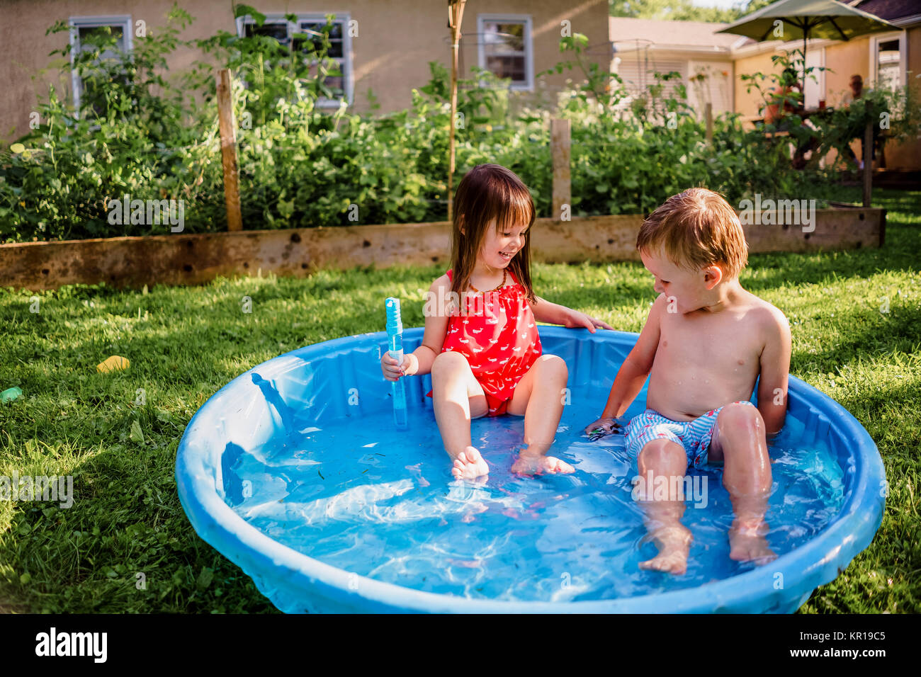 Junge und Mädchen sitzen in einem Planschbecken im Garten Stockfoto