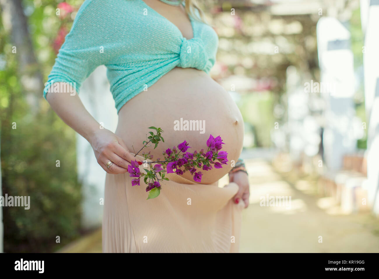 Schwangere Frau, die eine Blume Stockfoto