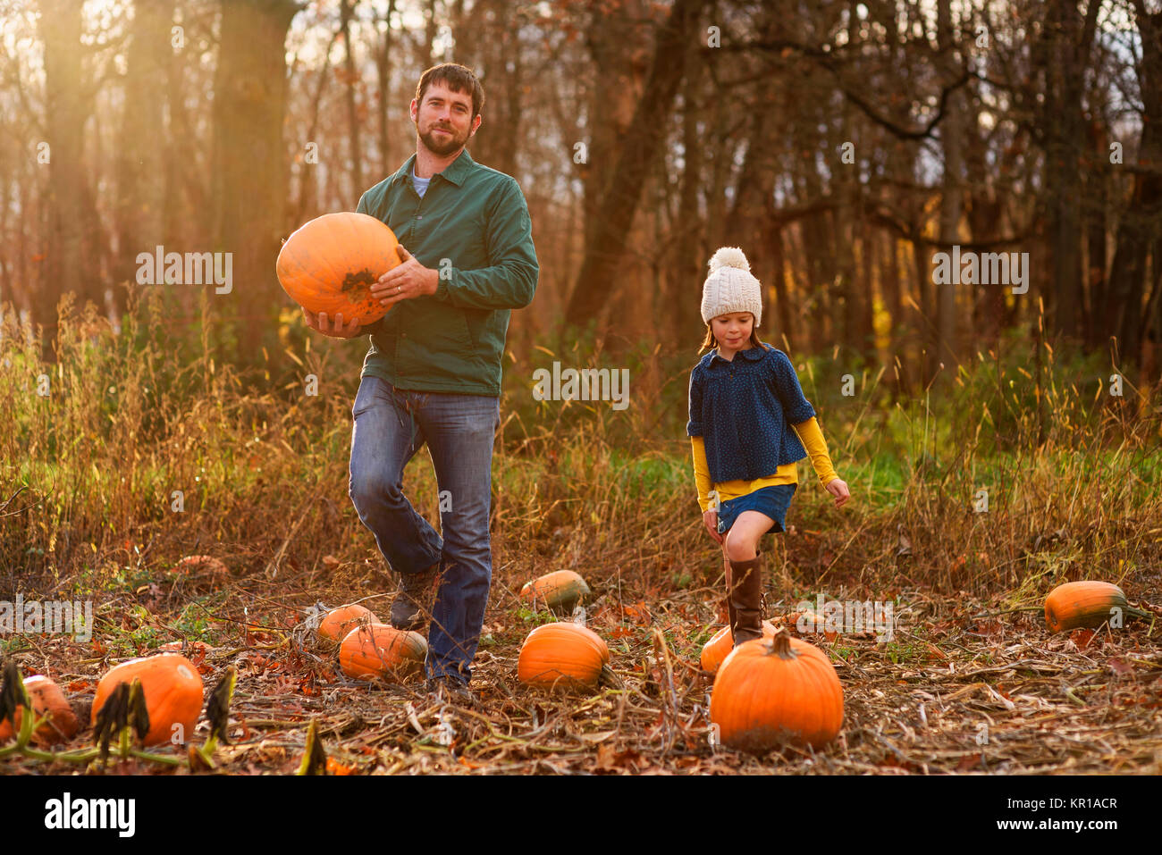 Vater und Tochter Kommissionierung Kürbisse in einem Pumpkin Patch. Stockfoto
