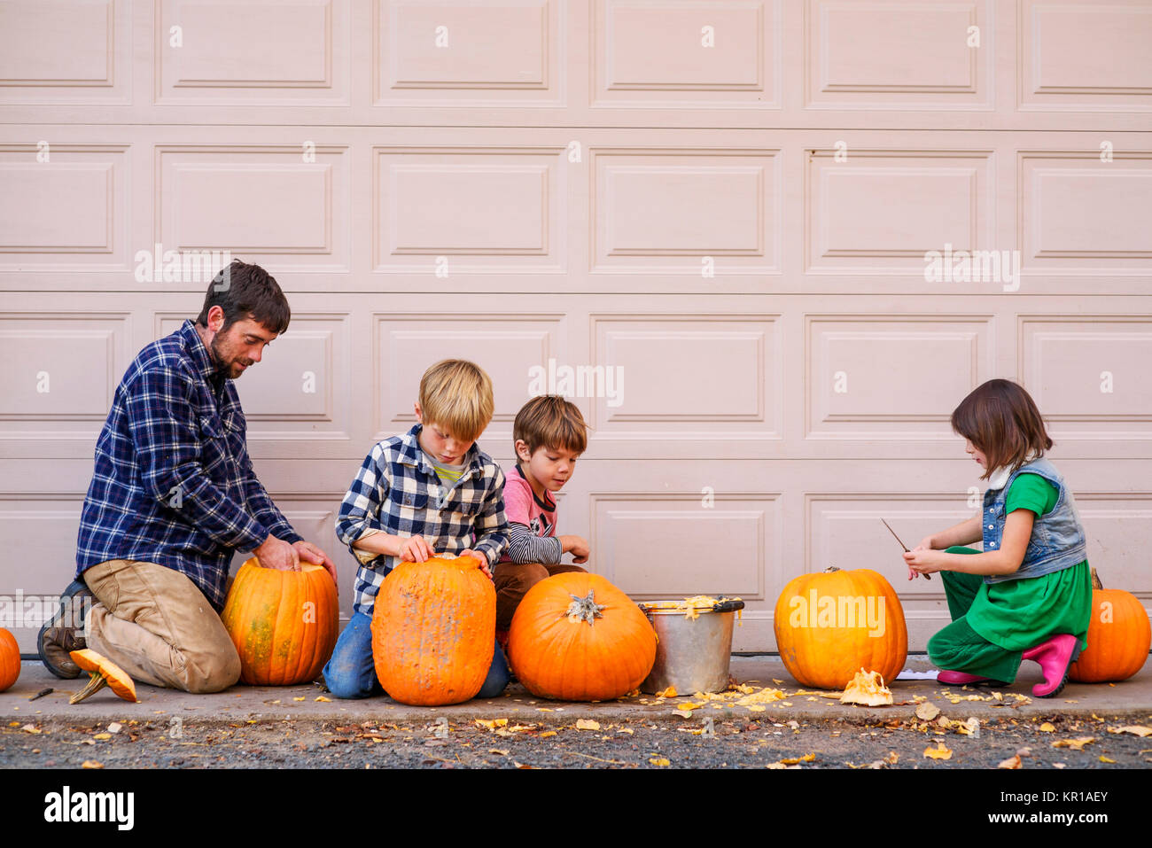 Vater und drei Kinder schnitzen Halloween Kürbisse Stockfoto