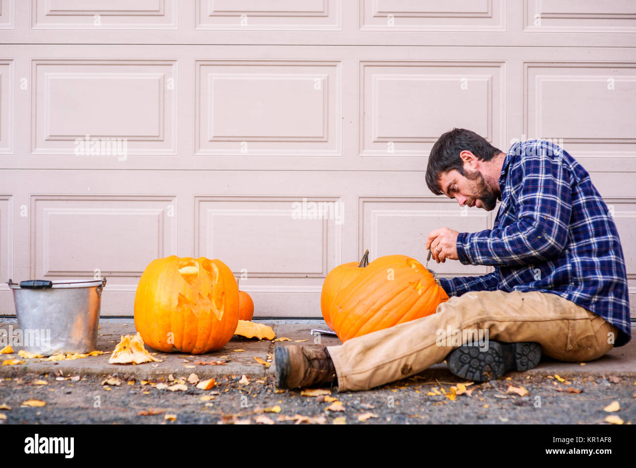 Mann sitzt im Freien das Schnitzen eines Halloween Kürbis Stockfoto