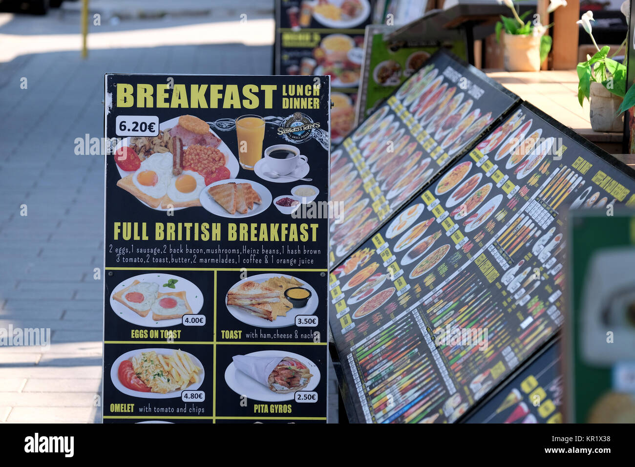 Ein strassenrand Cafe in Rhodos, Griechenland temps Englische Touristen durch ein Schild für ein traditionelles englisches Frühstück und ist u=in Euro Stockfoto