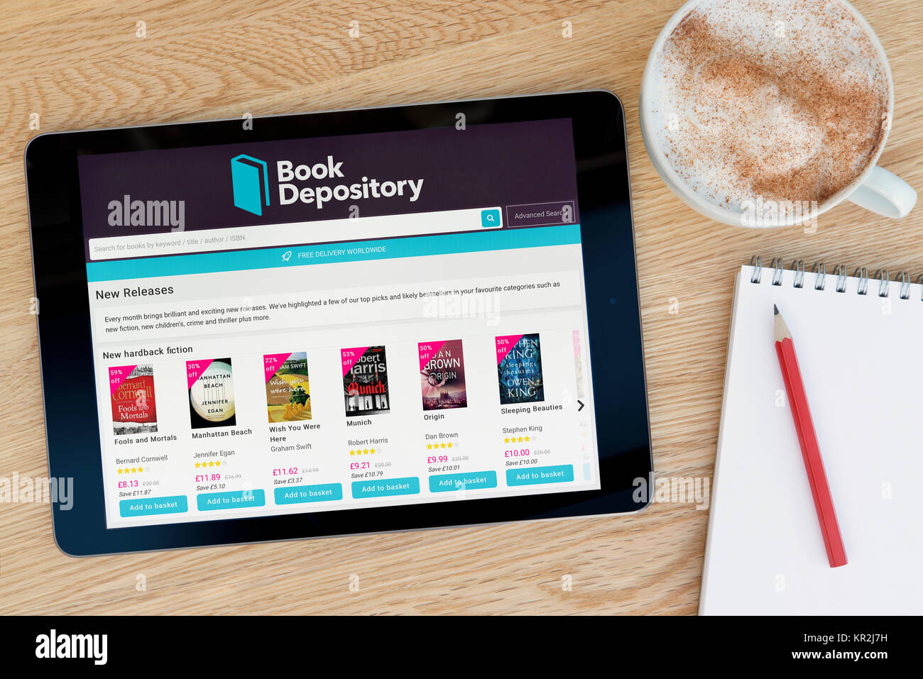 Die Book Depository Website auf einem iPad Tablet Gerät, das auf einem Tisch liegt neben einem Notizblock und Bleistift und eine Tasse Kaffee (nur redaktionell) Stockfoto