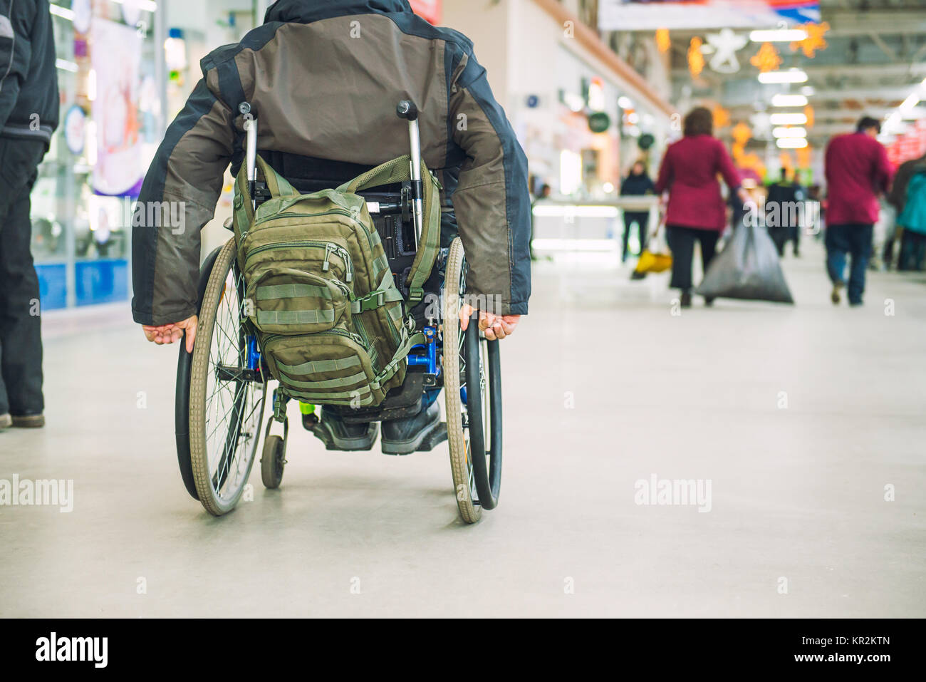 Kein Gesicht im Alter behinderte, behinderte Person auf Rädern Stuhl unter den Menschen ohne Behinderungen in die Mall von Markt. Selektive konzentrieren. Platz für Text Stockfoto