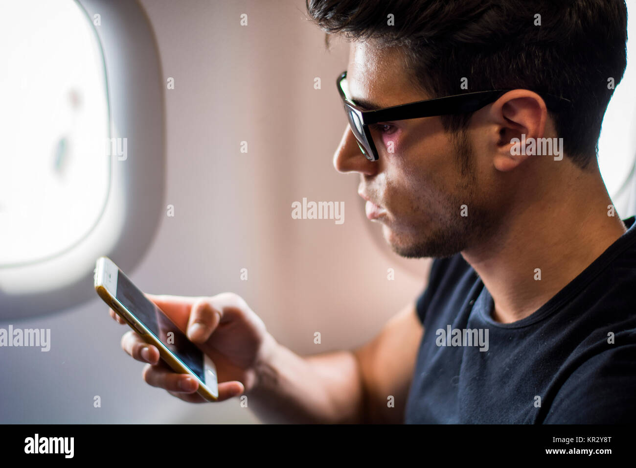 Junger Mann im Flugzeug Musik hören Stockfoto